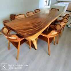 Meja makan trembesi Jepara dari kayu solid dengan serat alami dan desain live edge, dipadukan kursi kayu rotan elegan.